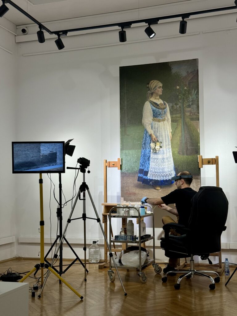 restauratorul Radu Tătaru, lucrând la o pictură ce înfățișează o femeie în port popular săsesc